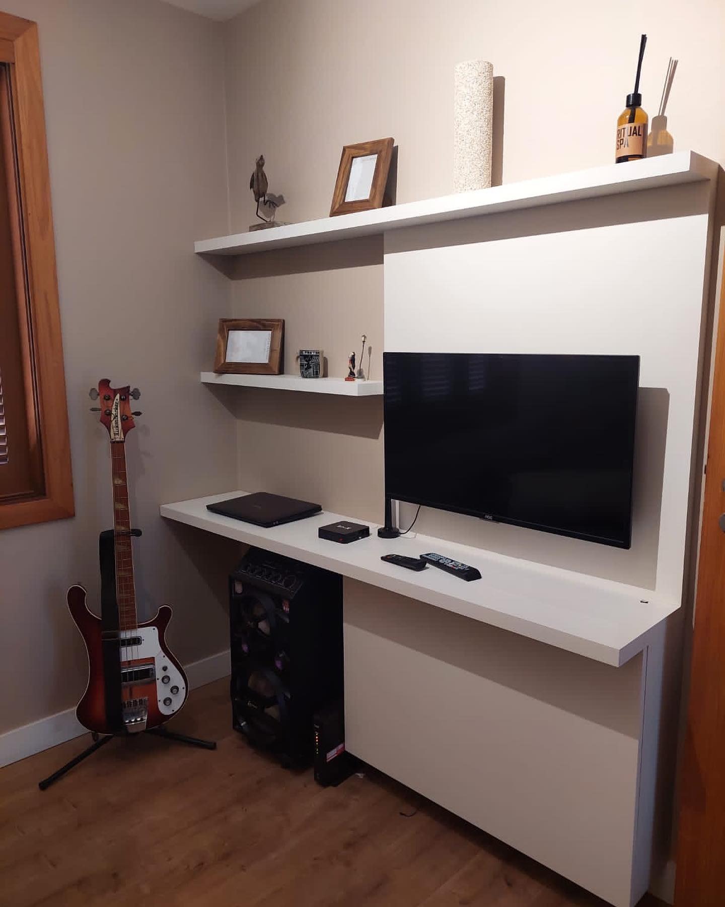 Home office com bancada suspensa, prateleiras e TV sob medida