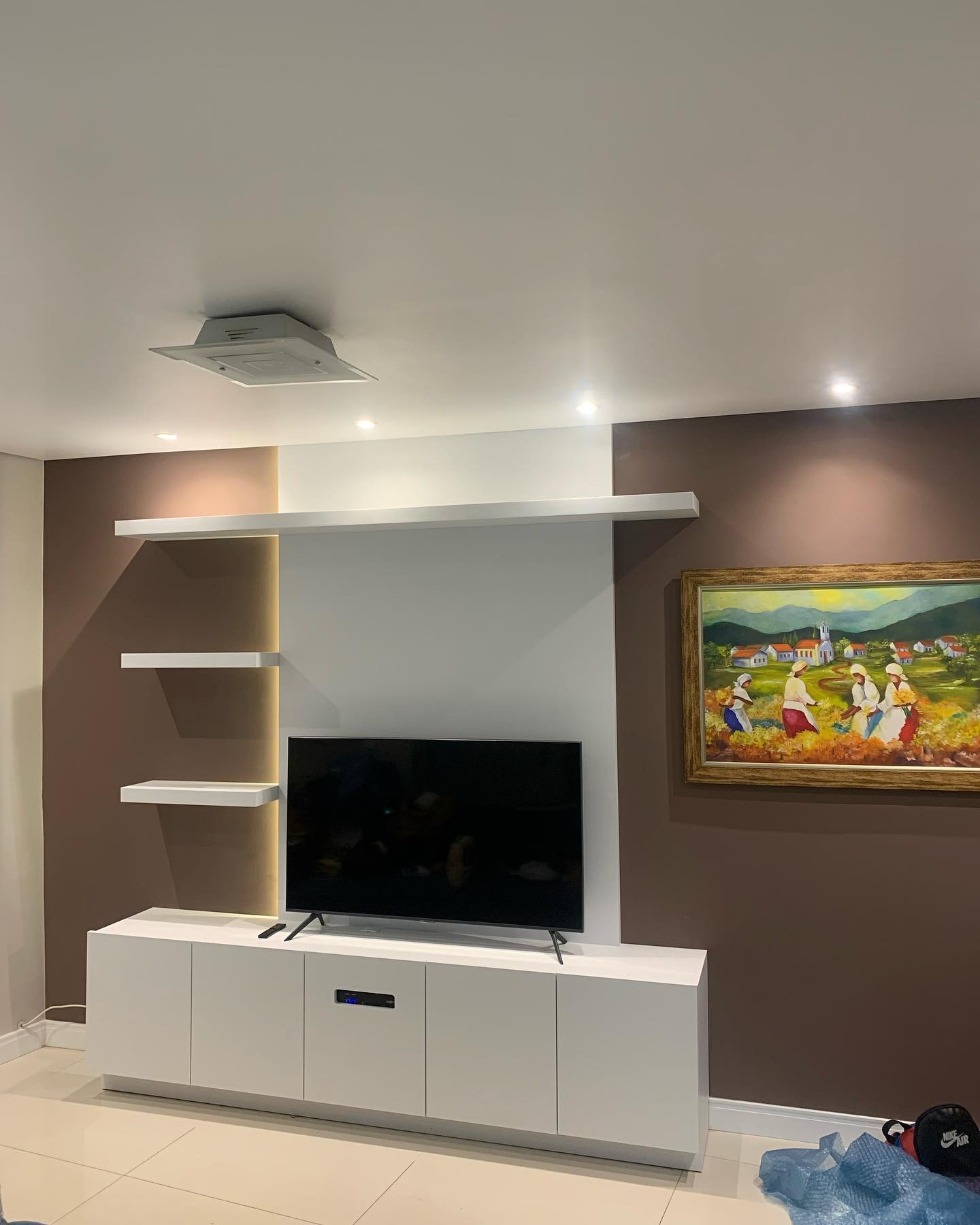 Painel de TV com rack branco e prateleiras iluminadas