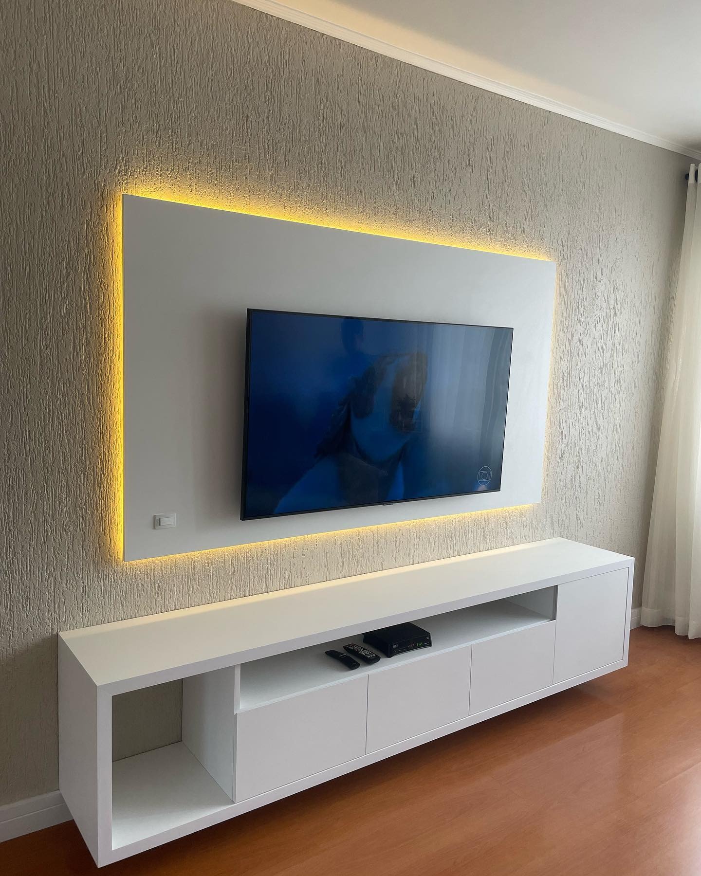 Painel de TV e rack branco sob medida com iluminação LED amarela